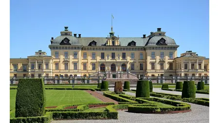 A castle with clipped boxwood hedges in front.