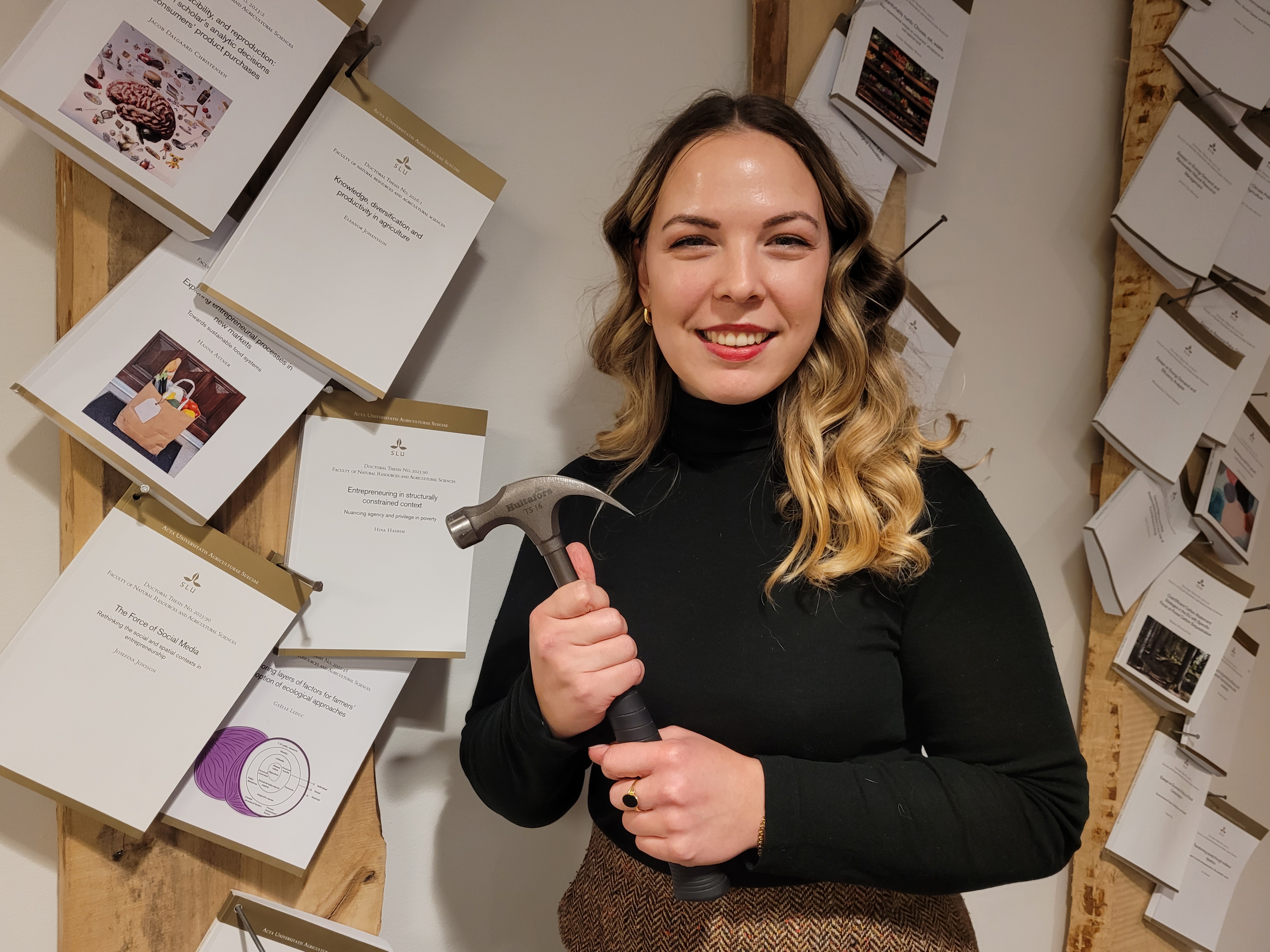 Eleanor Johansson standing in front of nailed PhD thesis.