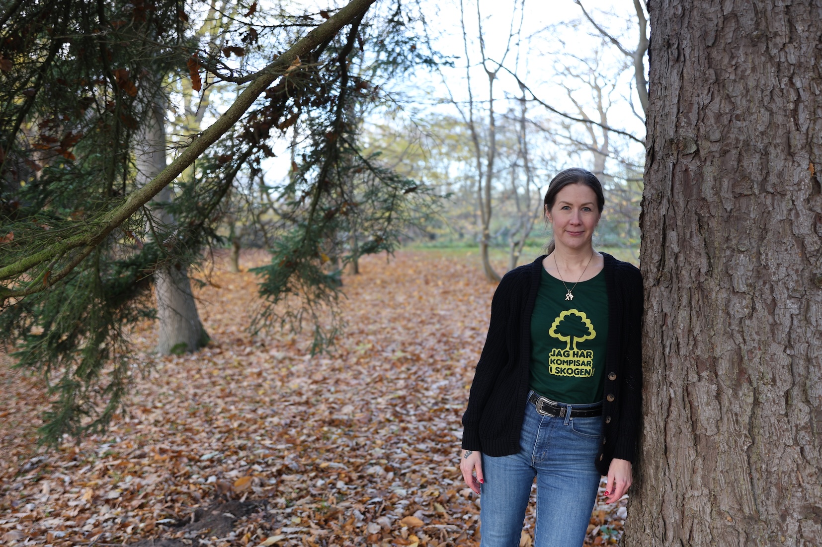 kvinna står lutat mot ett träd