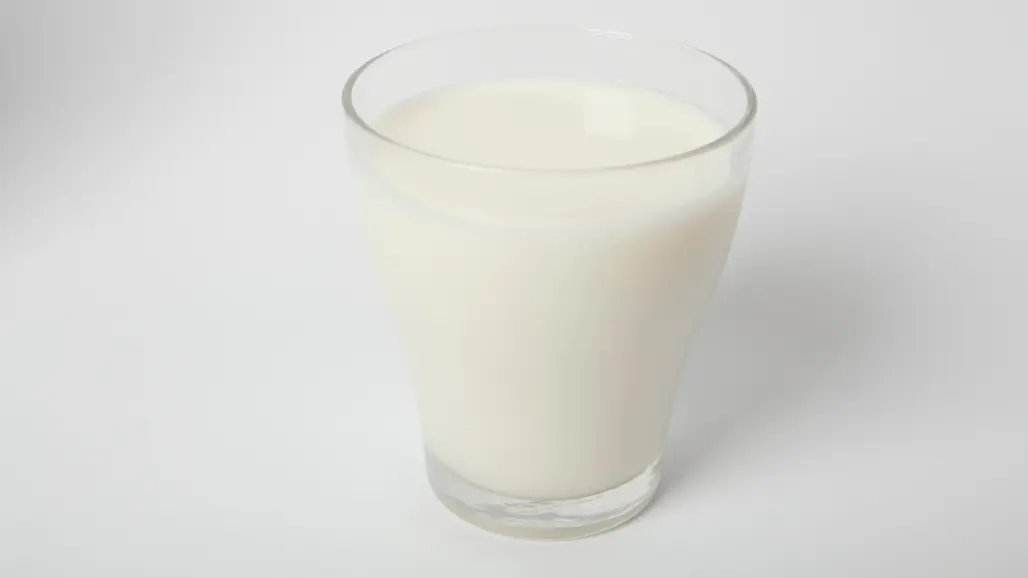 Ett glas med mjölk på vit bakgrund. Glaset är fyllt nästan till kanten och står i centrum av bilden, fotograferat med mjukt ljus som framhäver den vita dryckens släta yta.