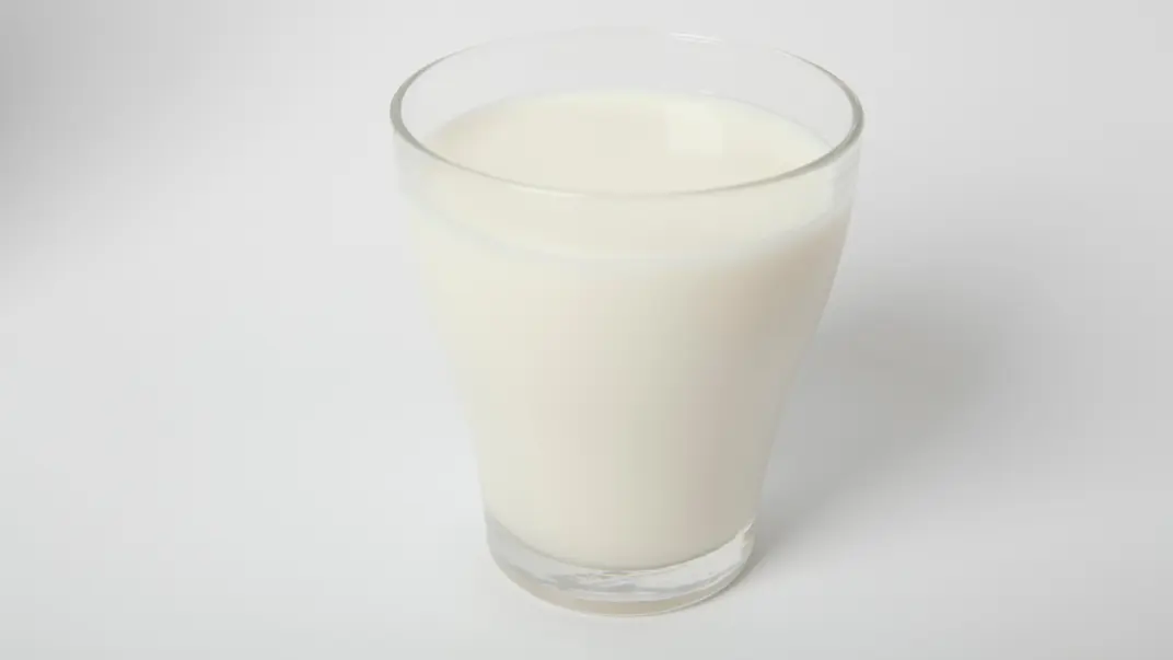 Ett glas med mjölk på vit bakgrund. Glaset är fyllt nästan till kanten och står i centrum av bilden, fotograferat med mjukt ljus som framhäver den vita dryckens släta yta.