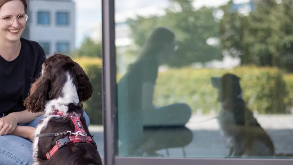Photo of a woman (Emma Thilén, SLU) sitting outdoors with a spaniel-type dog.