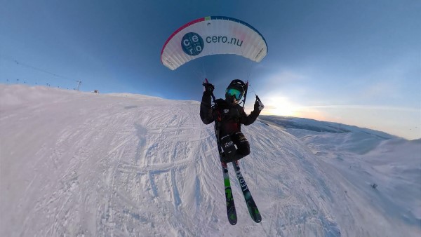 skidåkare med kite flyger ovanför skidbacke