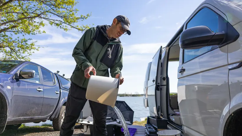 En person häller vatten i en hink.