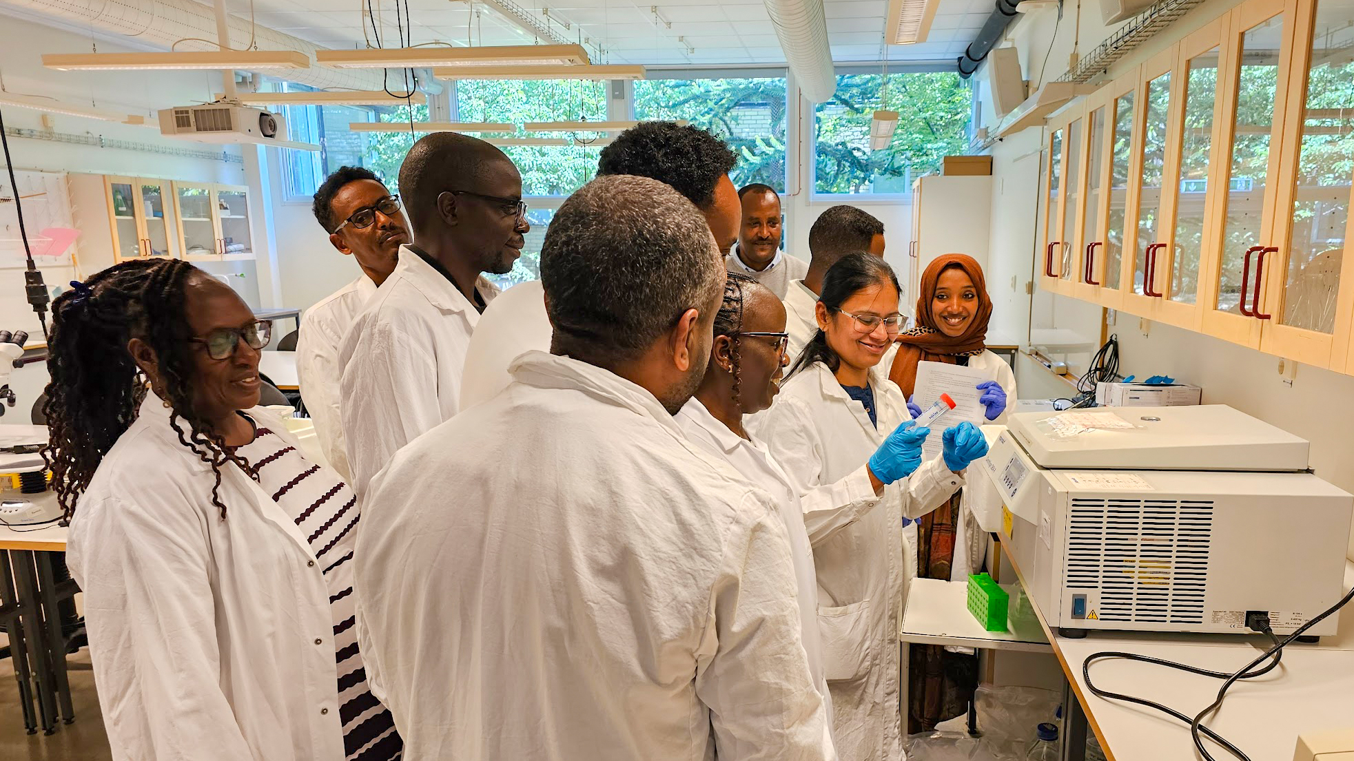 Många personer i laboratorierockar inomhus. Foto.