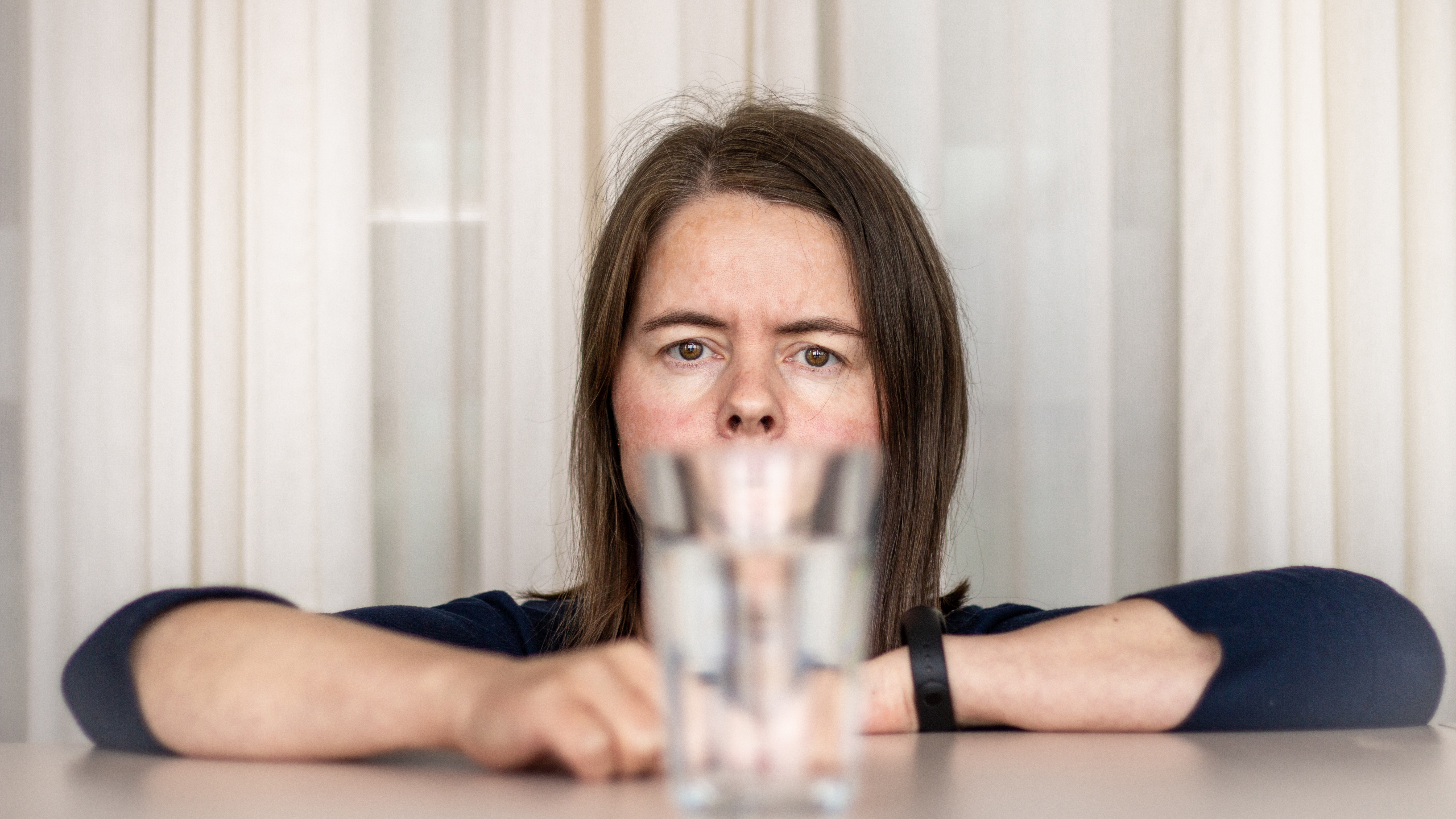 Photo of a woman looking through a filled water glass.