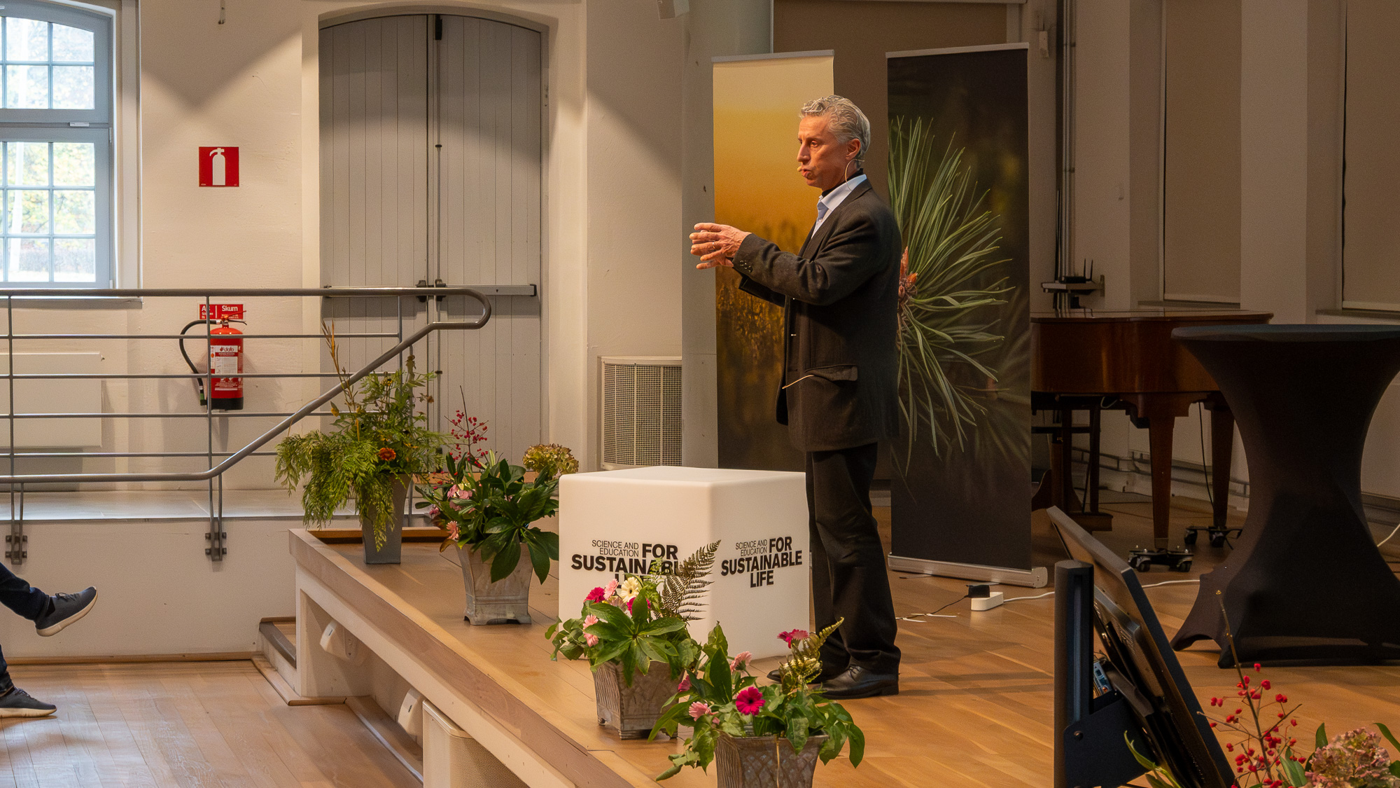 En talare på en scen med blommor. Foto.