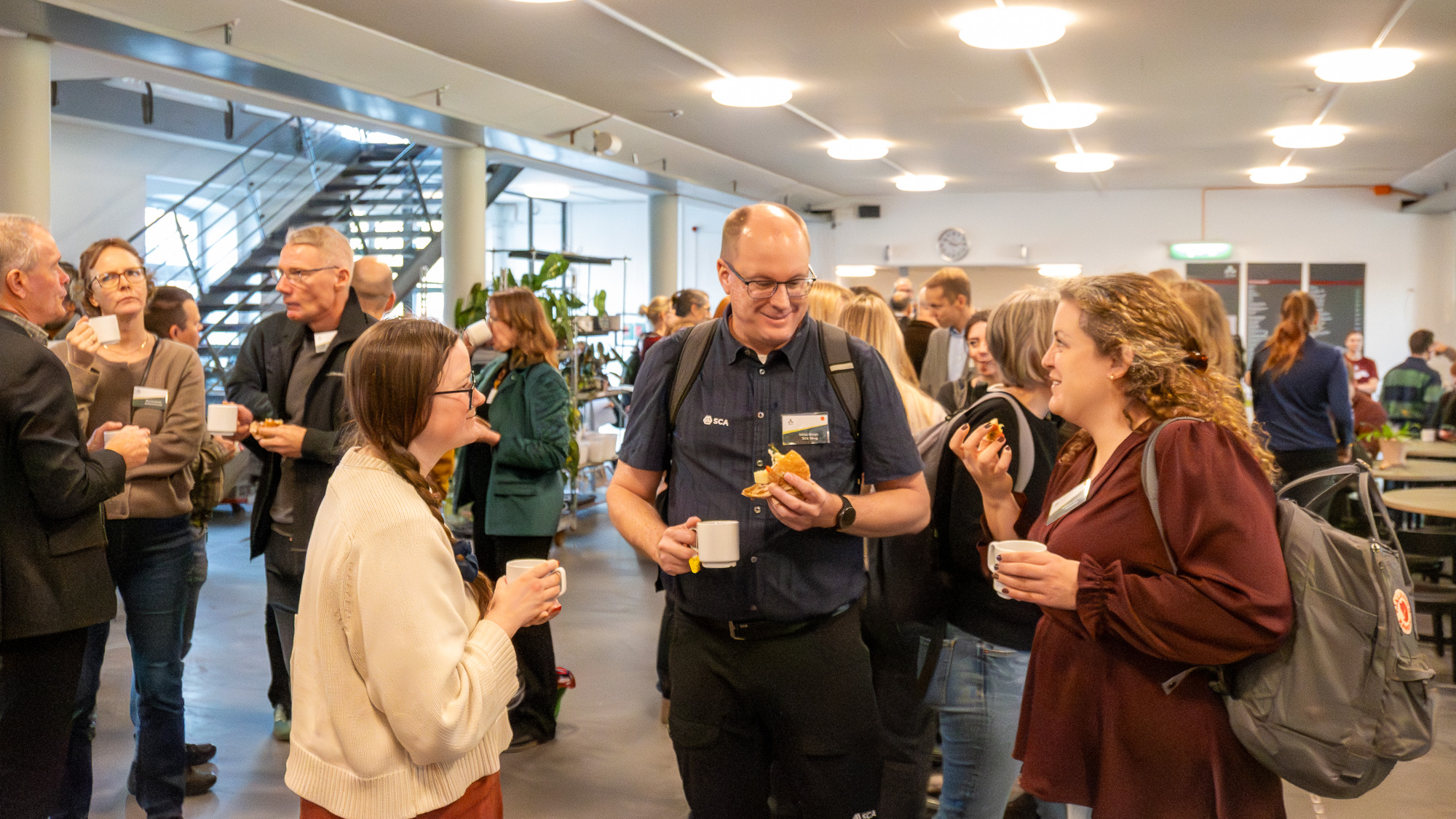 Många personer minglar inomhus. Foto.