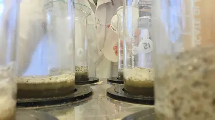 Person i laboratorium som häller vätska