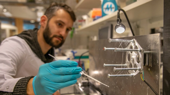Foto av en manlig forskare som arbetar med att spinna artificiell spindeltråd i laboratoriet.