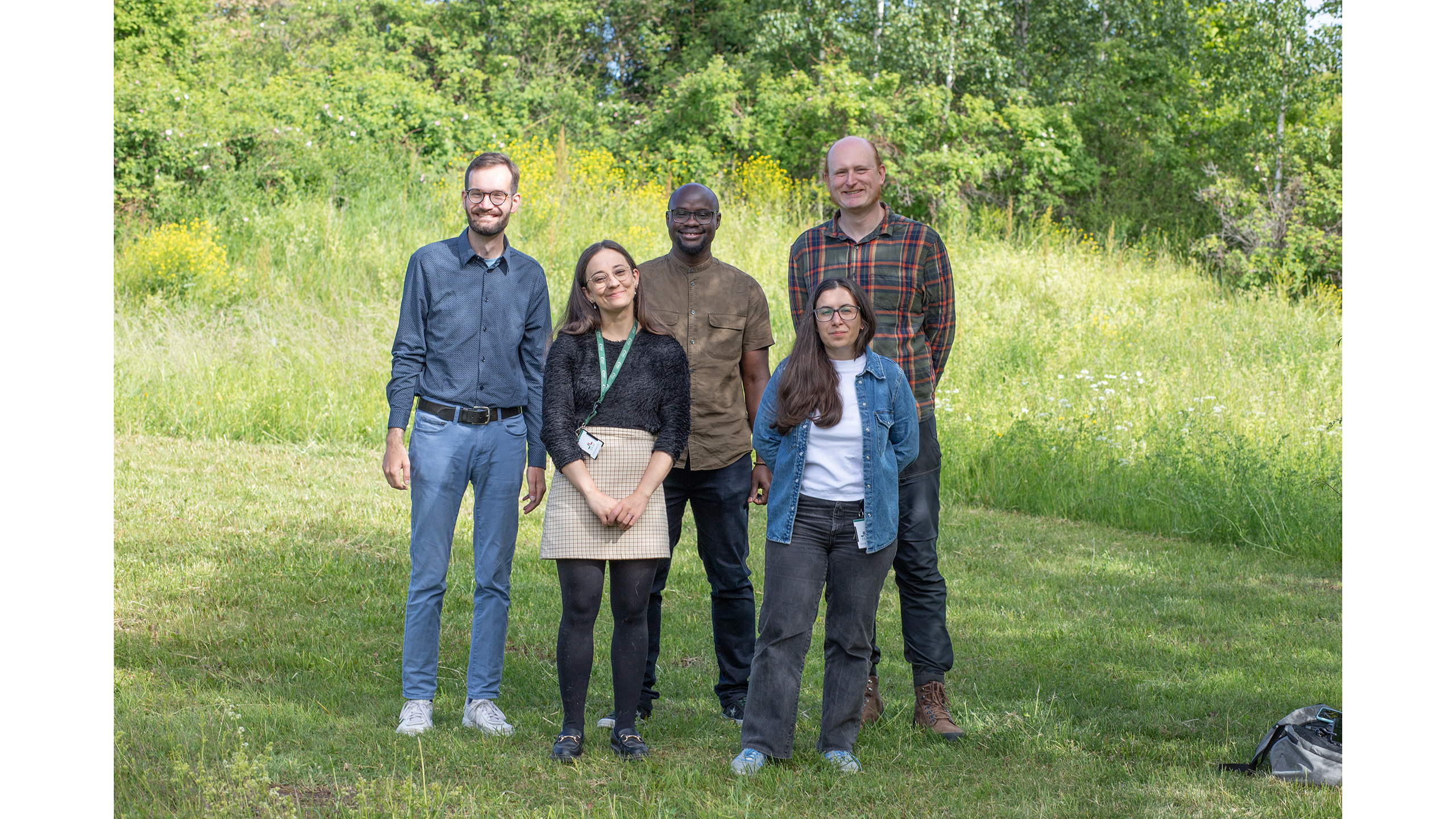 Fem personer står på en gräsplan.