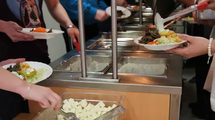 People putting food on plates. Photo.