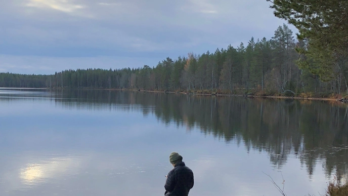 Person by a lake with forest in the background
