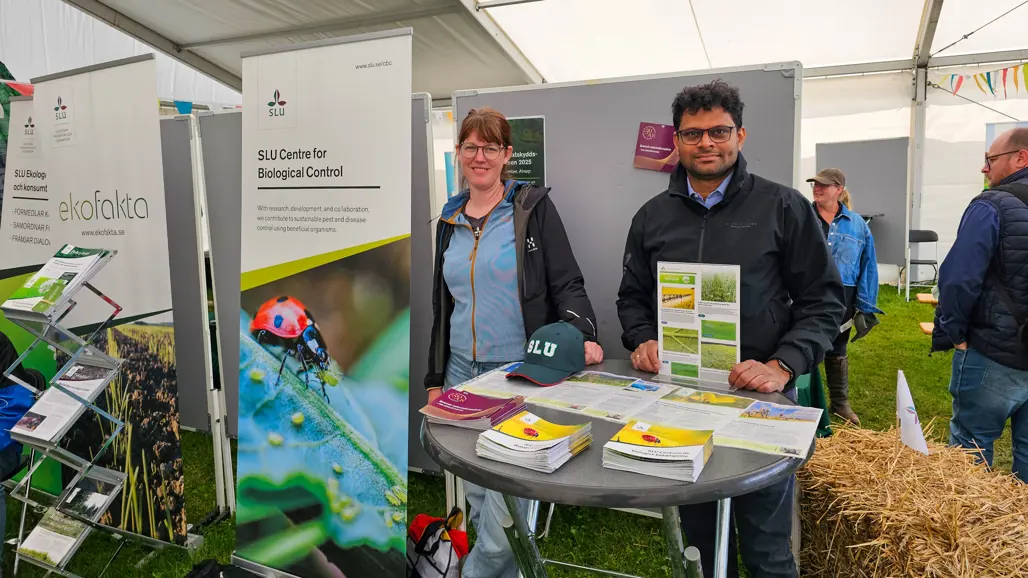 Two people in a booth with presentation materials. Photo.
