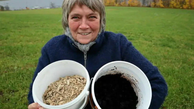 Anne-Kristin står med två hinkar i famnen. Foto.