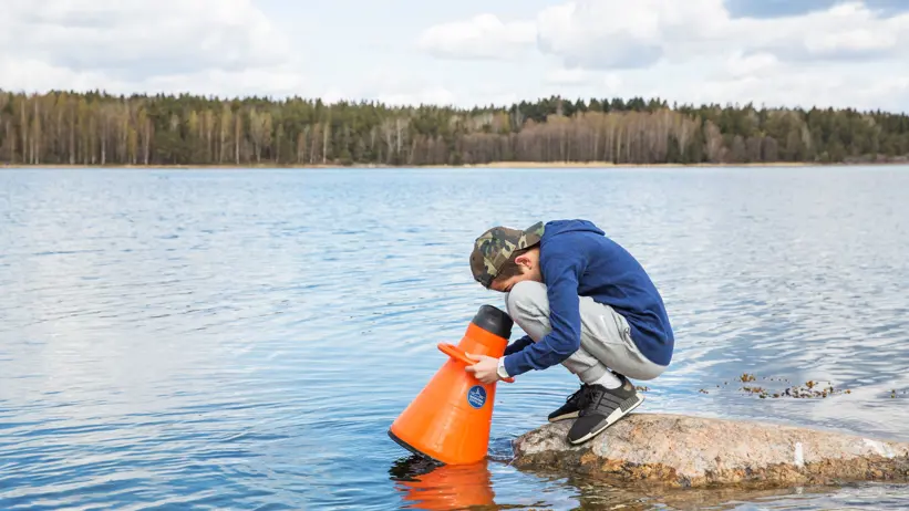 Pojke undersöker livet under vattenytan med en vattenkikare