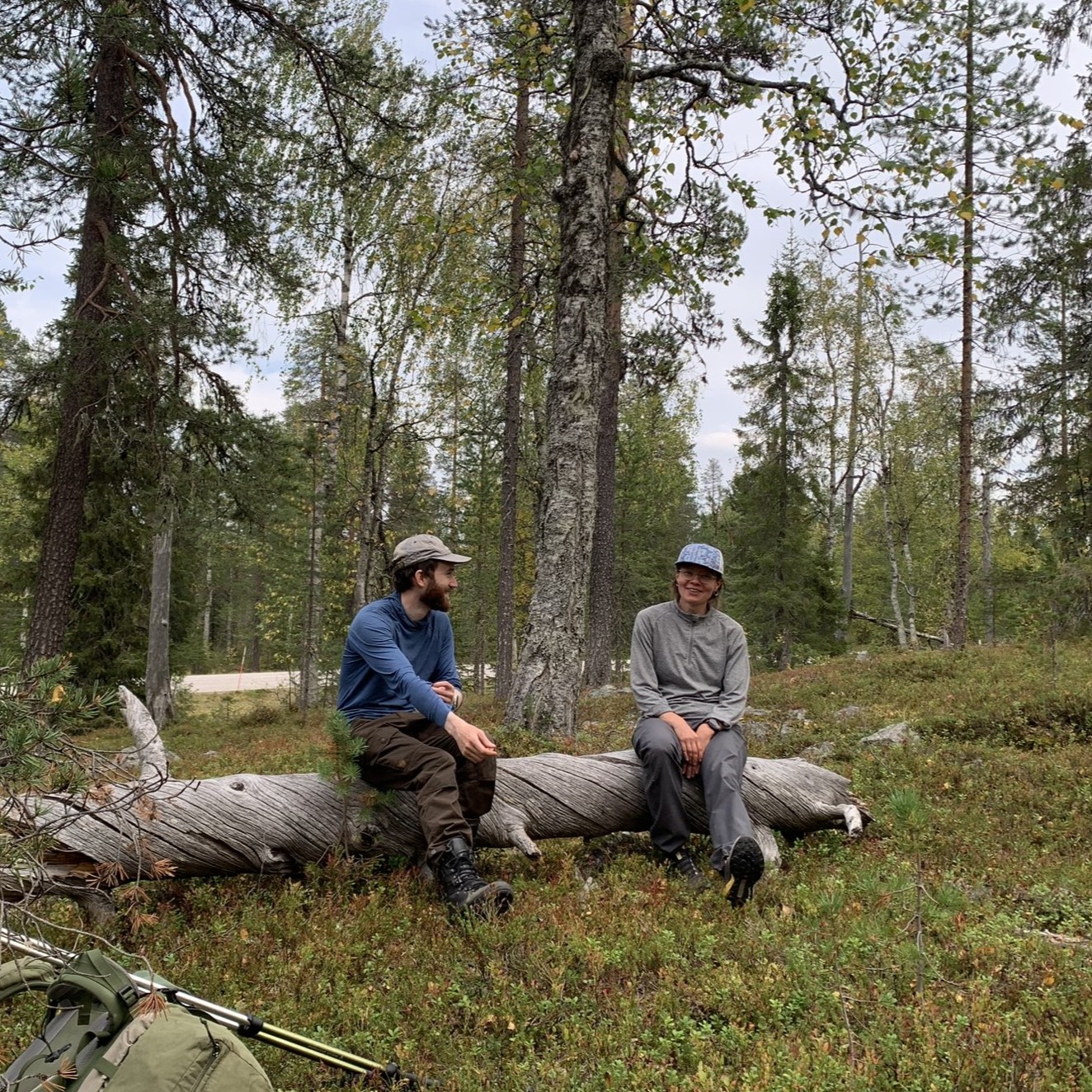 Två personer sitter på en trädstam och pratar.