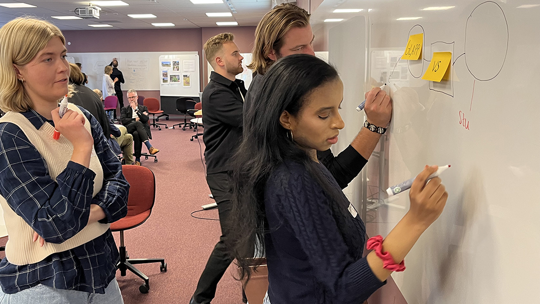 Tre studenter skriver på en whiteboard