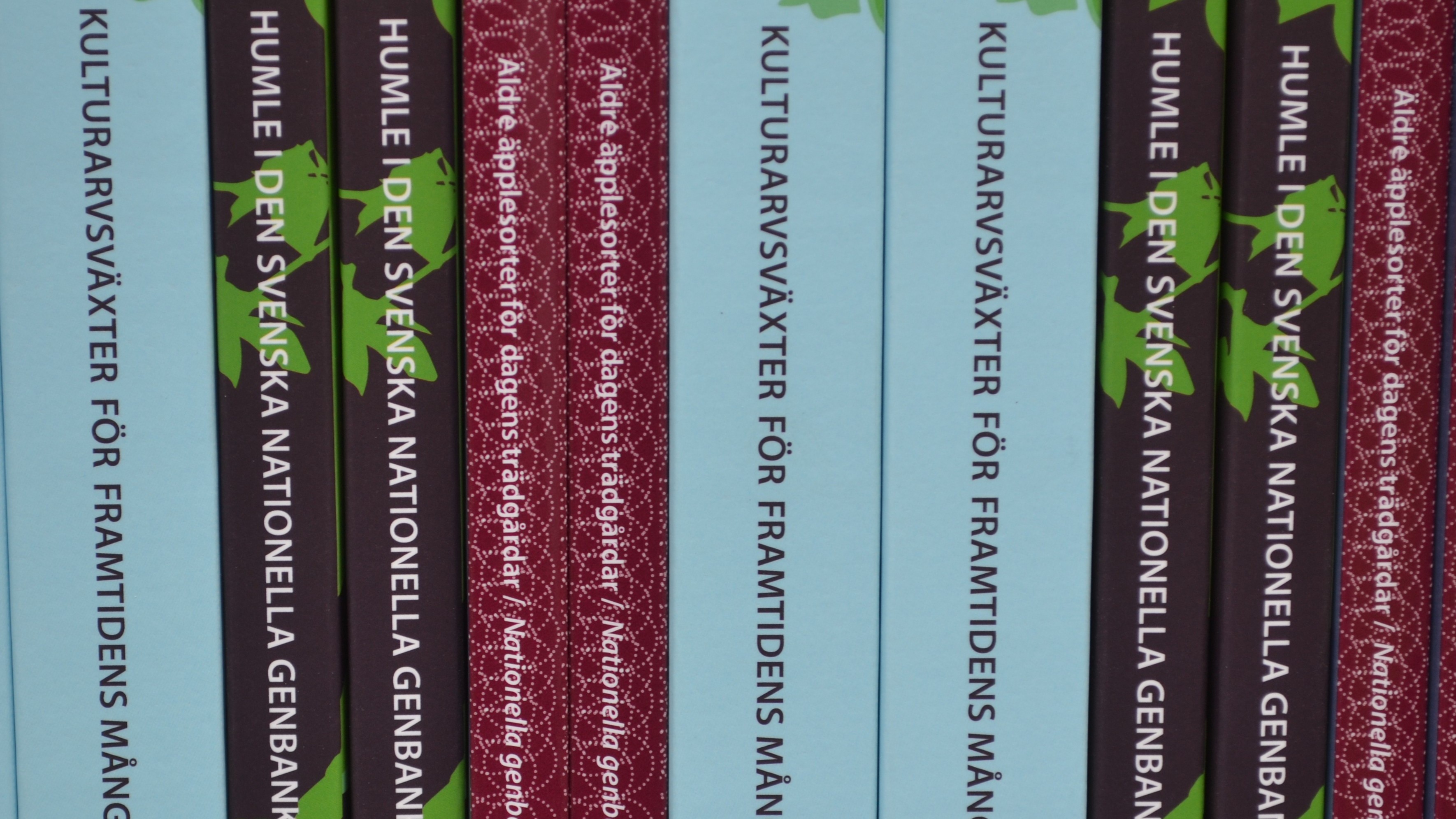 Böcker med lila och blå ryggar står i en bokhylla. Bara bokryggarna syns. 