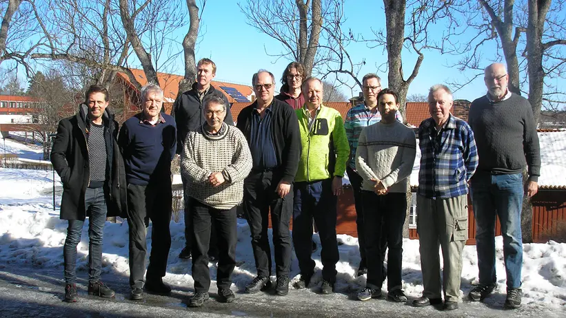 11 personer på rad i snölandskap. Foto
