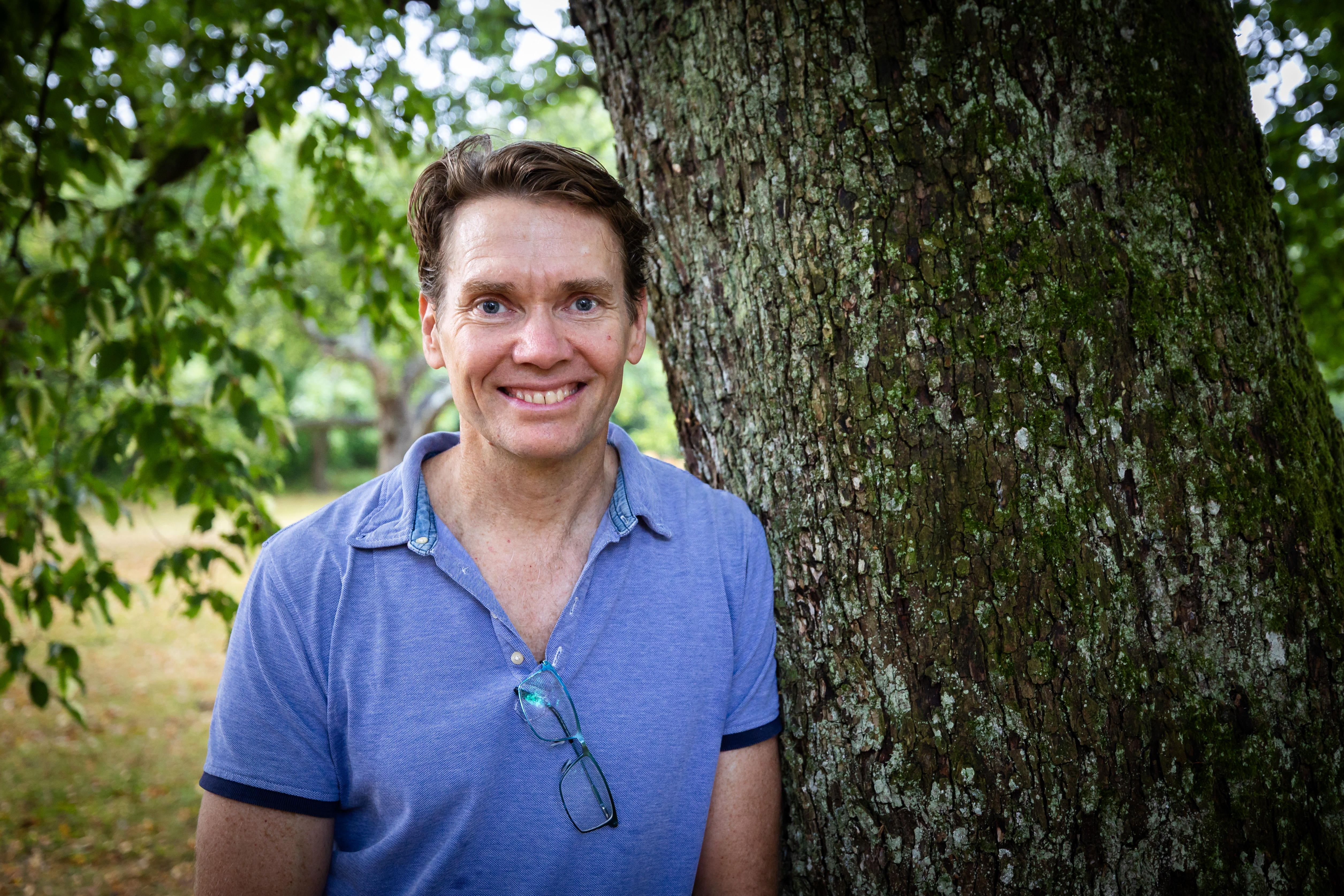 man står lutad mot ett träd