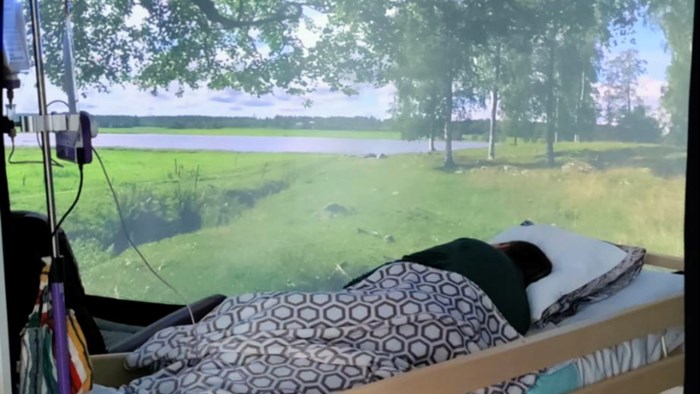 A person is lying in a bed and on the wall is a picture of beautiful nature. Photo.
