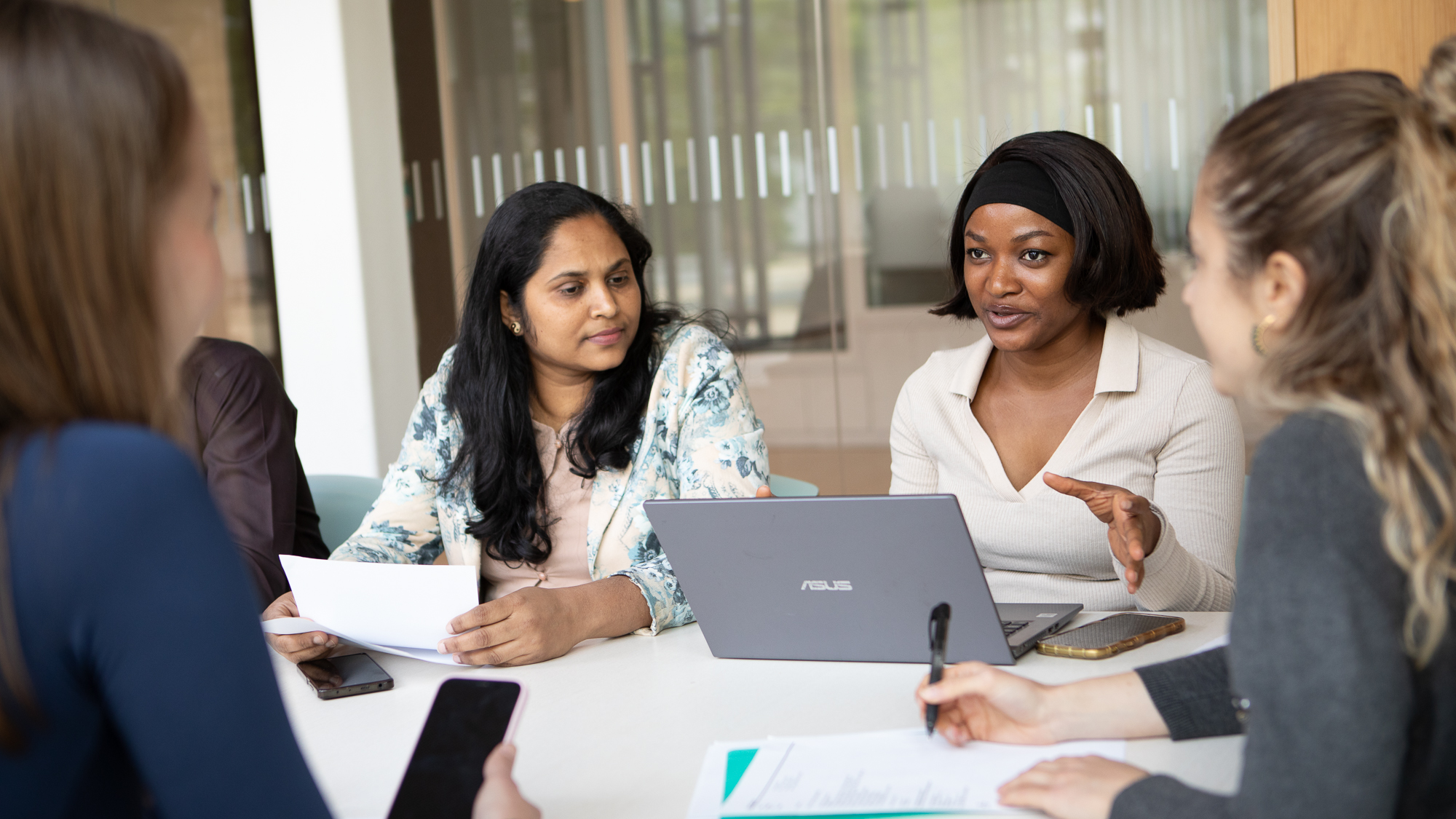 Four students sitting around a table, talking.