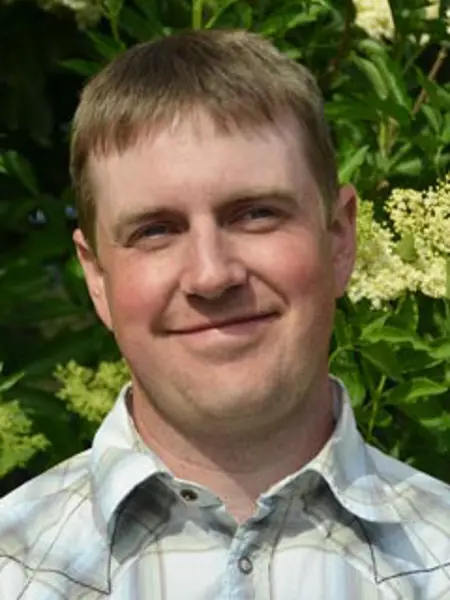 Porträttbild på David Johansson med blommande fläderbuske i bakgrunden. Foto.