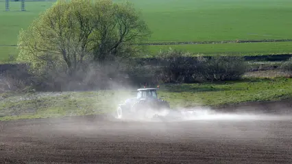 Foto av traktor som harvar en åker.