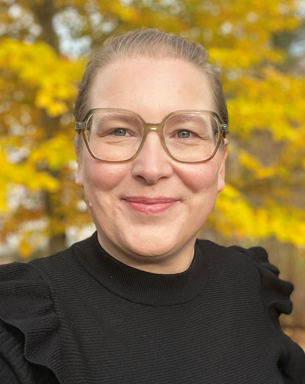 A smiling woman with glasses and a black sweater. Photo.