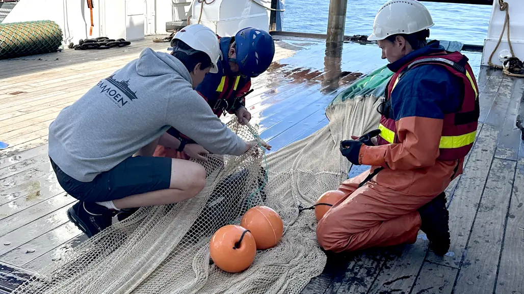 Four men lifting out a camera from a trawl