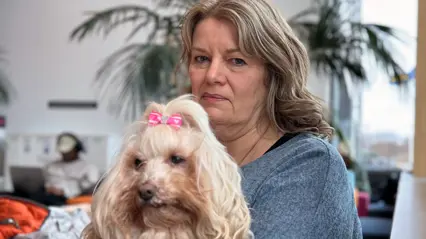 En kvinna sitter med sin hund i knäet.