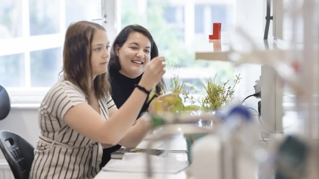 Två studenter tittar på en växt i labbet.