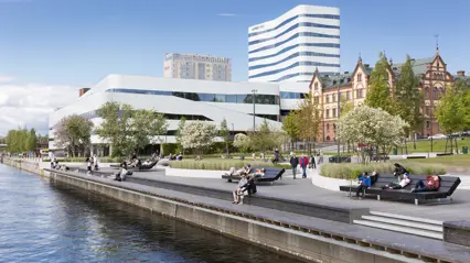 Walkway by the water in a city. In the background, modern and older buildings. Photo: Calle Bredberg/Visit Umeå
