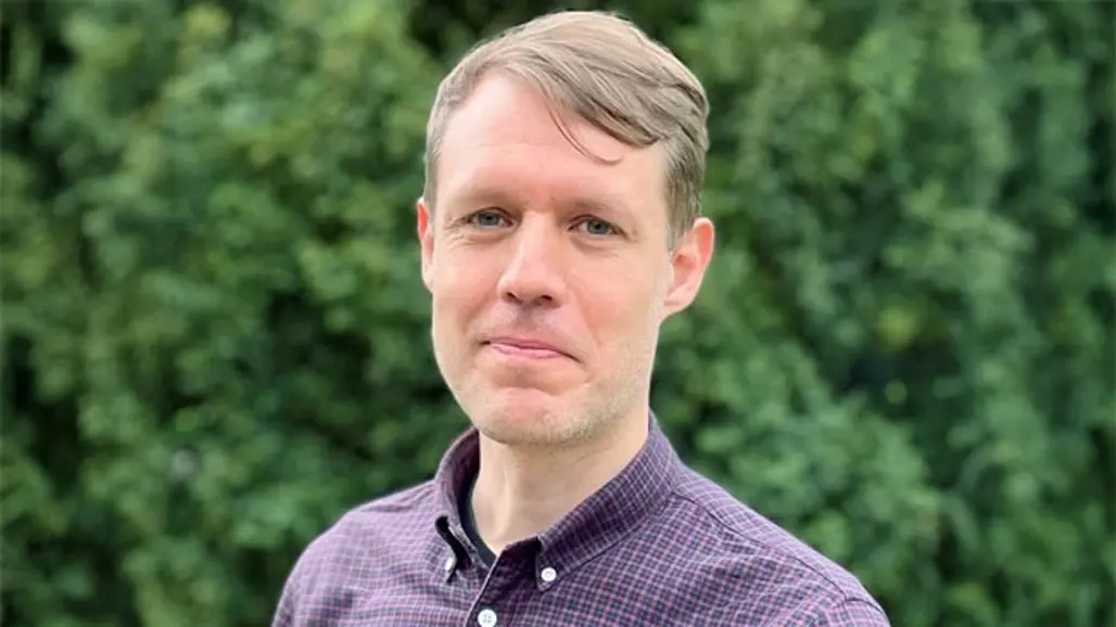 Man med kort hår och rutig skjorta