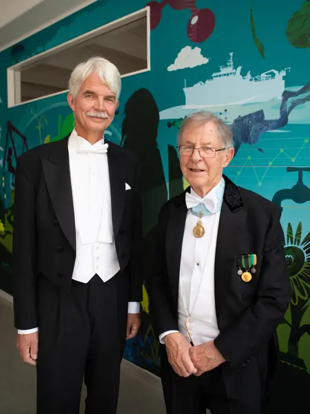 Två män i frack tittar glada in i kameran.