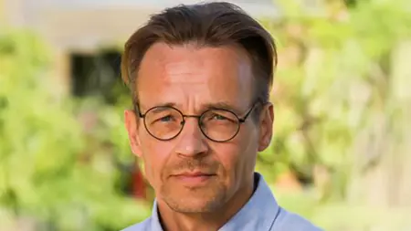 En man med glasögon utomhus. Foto.