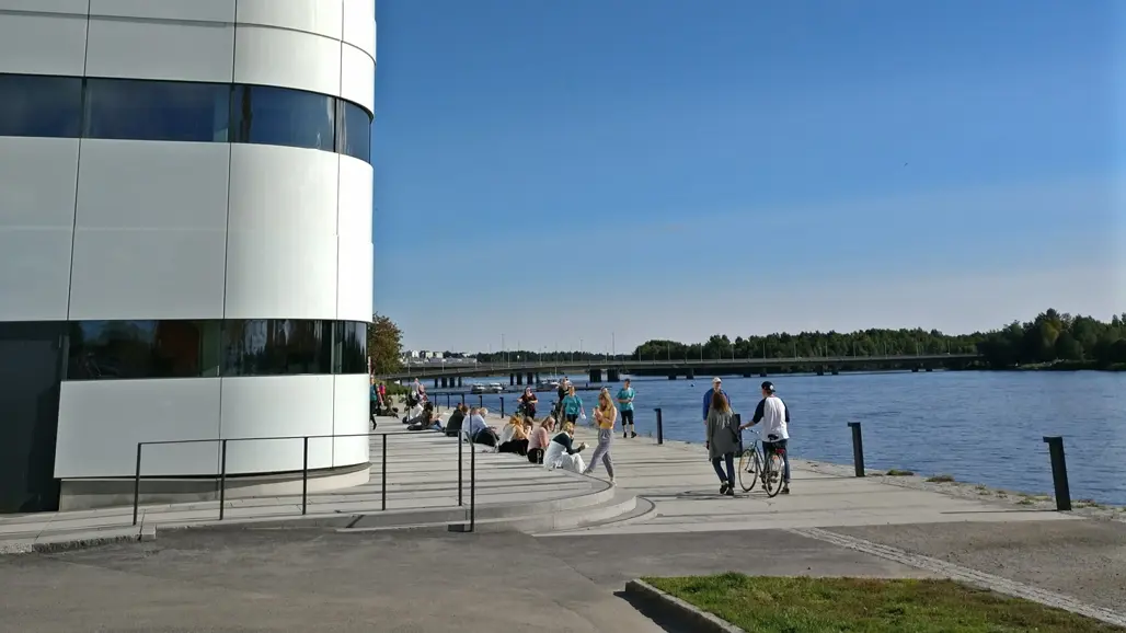 En älv, ett hus och människor. Foto.