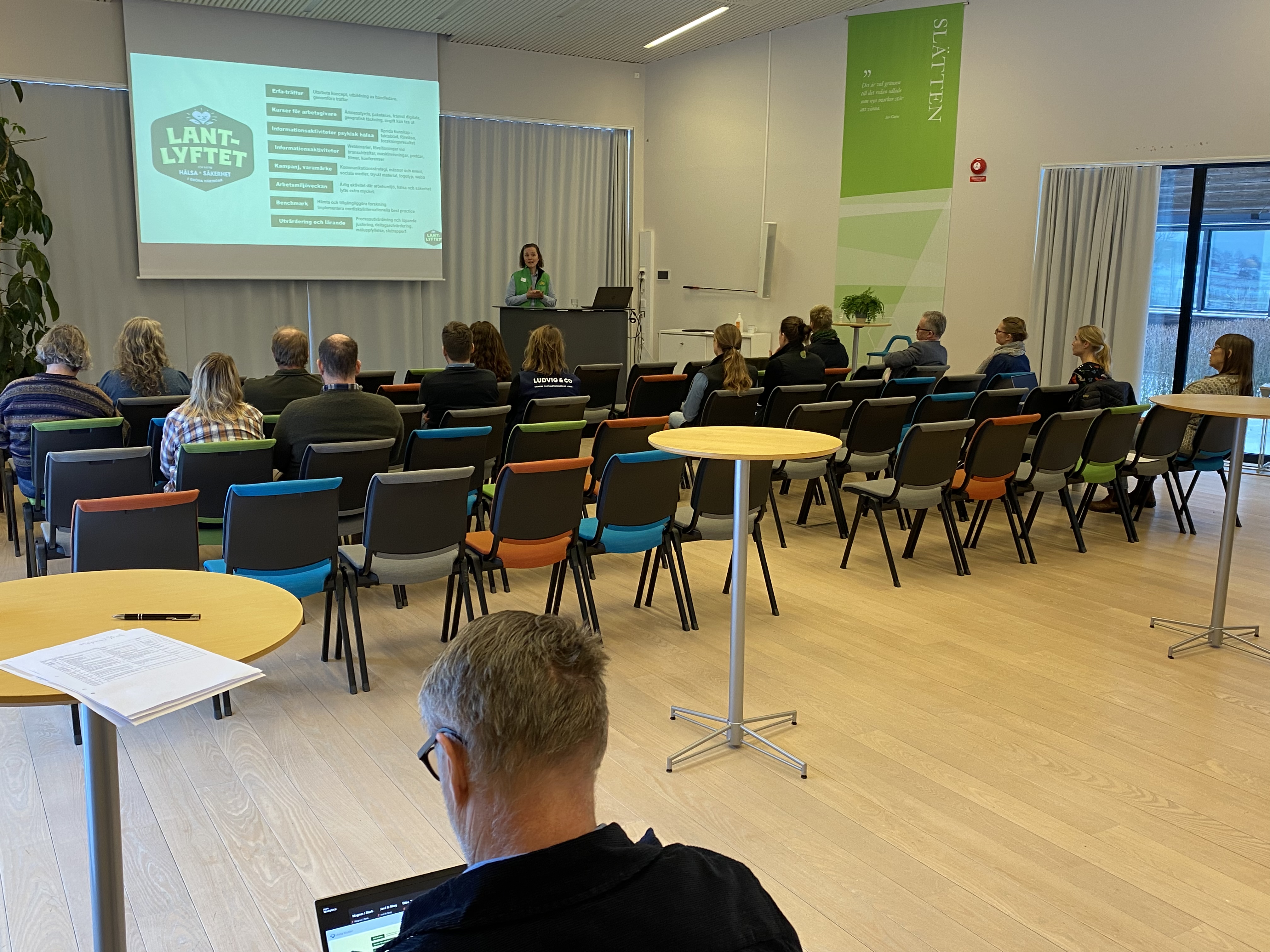 En föredragshållare talar inför publik. Foto.