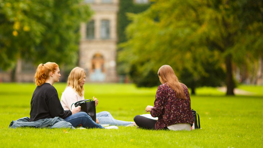 Tre studenter på gräsmattan framför slottet i Alnarp.
