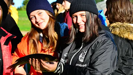 Elever håller i en fisk från sjön Bolmen.