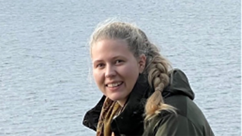 Närbild på Lisa Stensson med vatten i bakgrunden. 