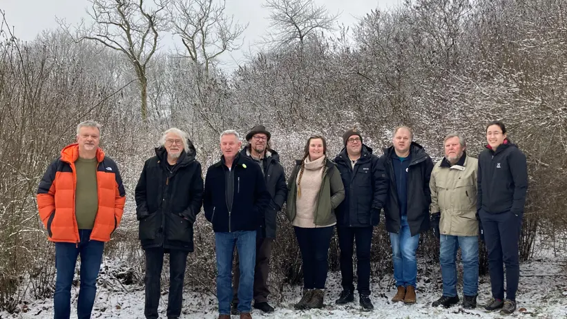 Nio människor på rad i vinterlandskap. Foto