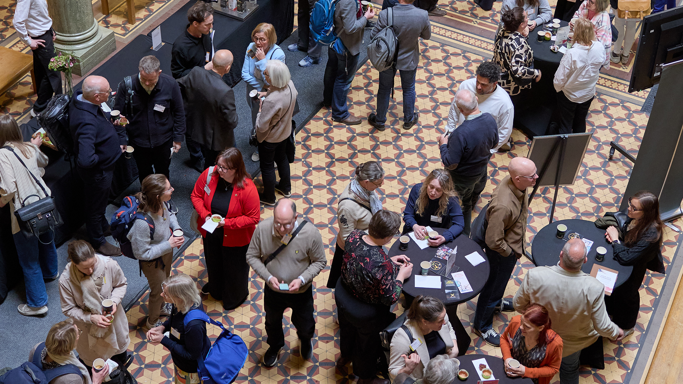 Foto ovanifrån på människor i konferenssal. 