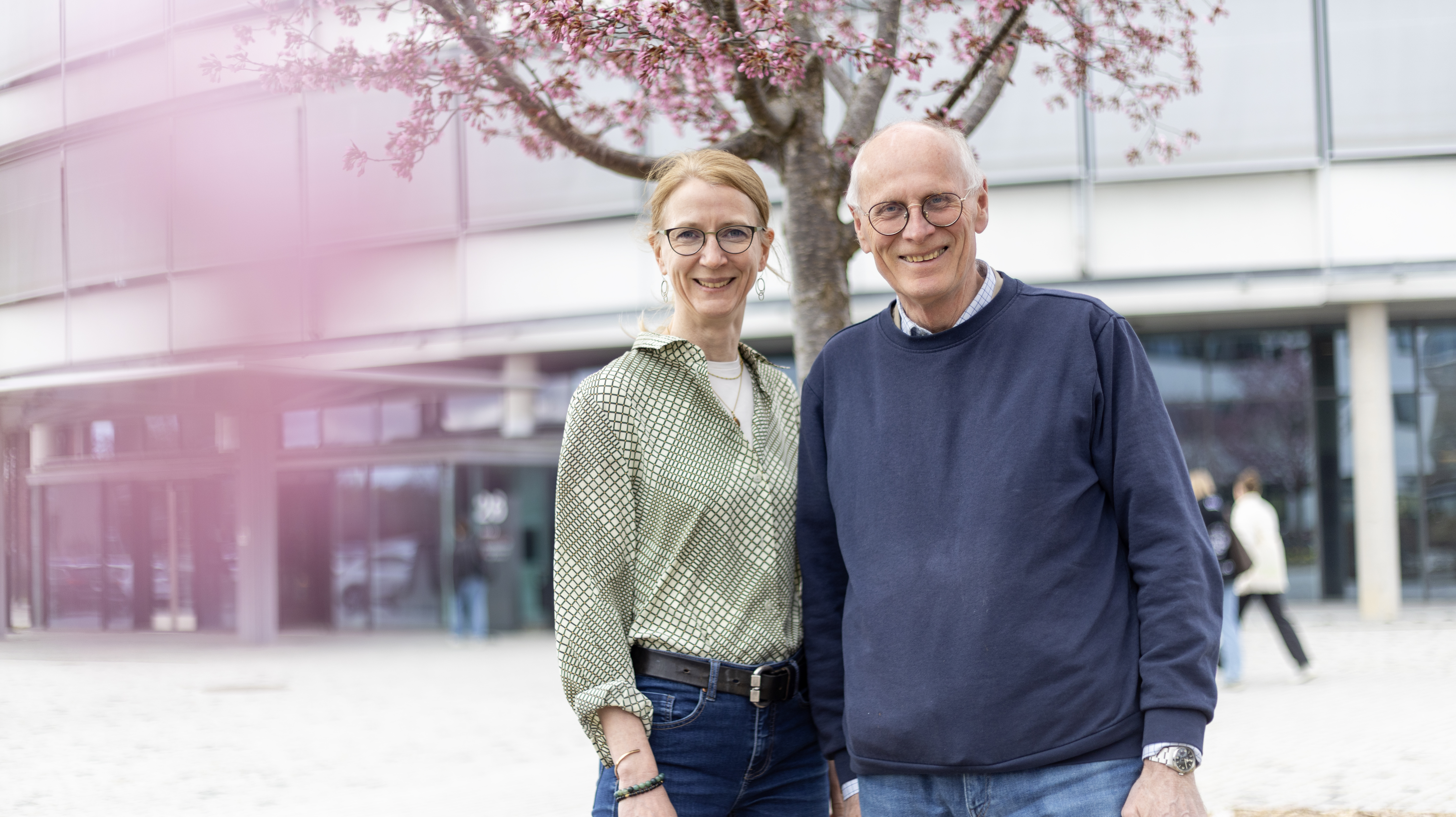 Photo of a male (Ivar Vågsholm, SLU) and a female (Sofia Boqvist, SLU) professor standing under a cherry tree in bloom outside the Swedish University of Agricultural Sciences.