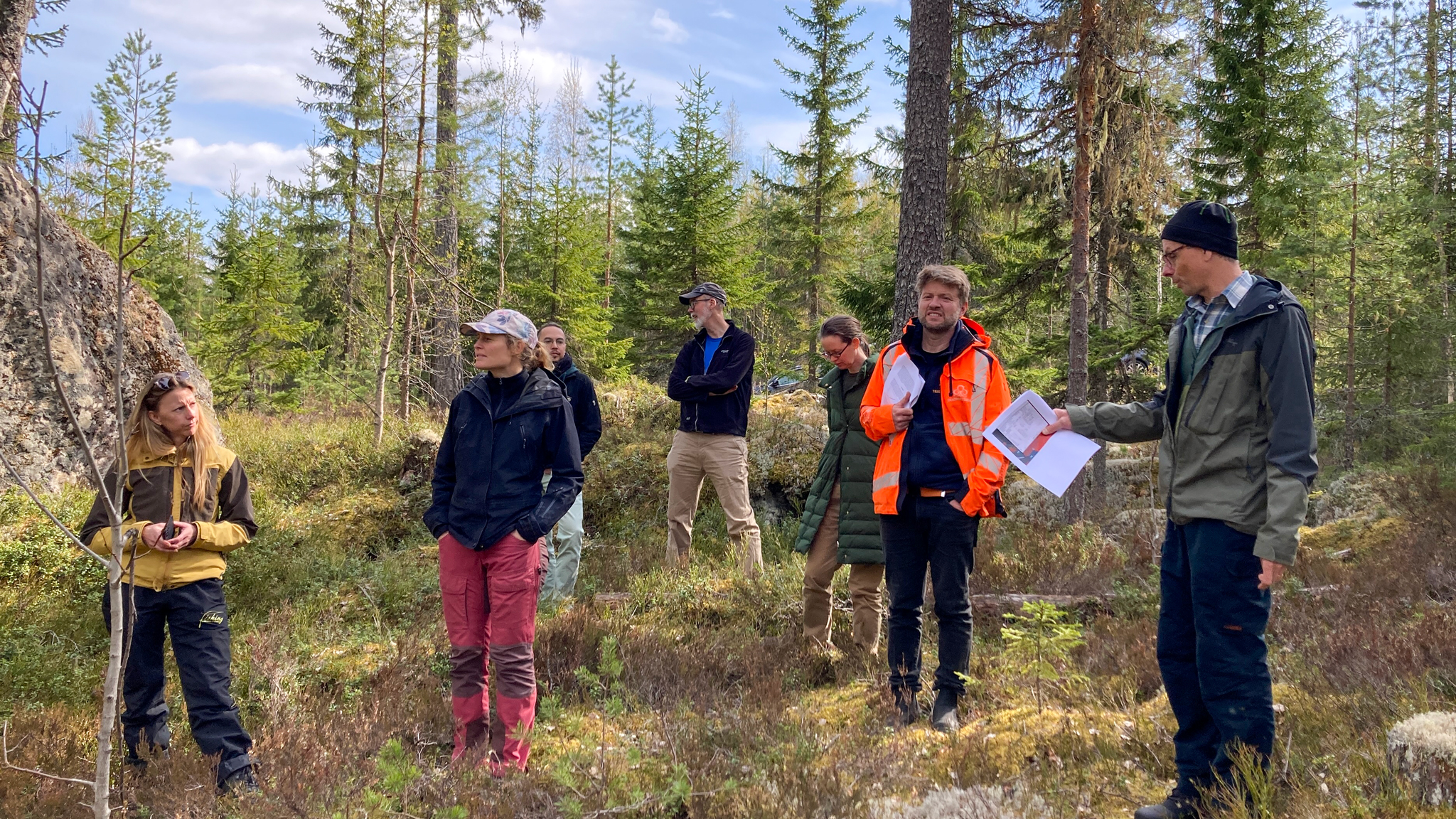 En grupp människor står i en skog. Foto.