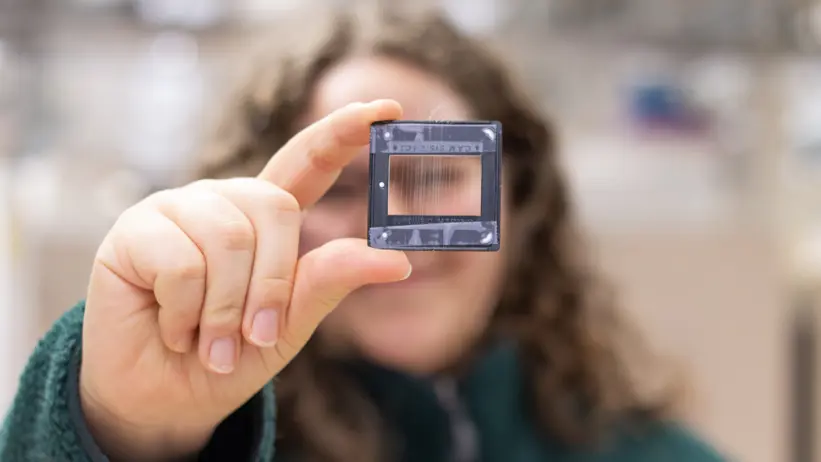 Foto av en kvinna (Viktoria Langwallner, SLU) i laboratorium, håller fram ett prov med artificiellt spunnen spindeltråd.