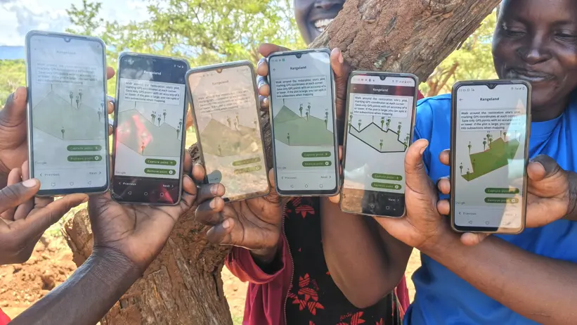 Community facilitators display restoration plots tracked using the Regreening App during a practical monitoring session at the Kawoson Livestock Café site. Photo F. Ndungu