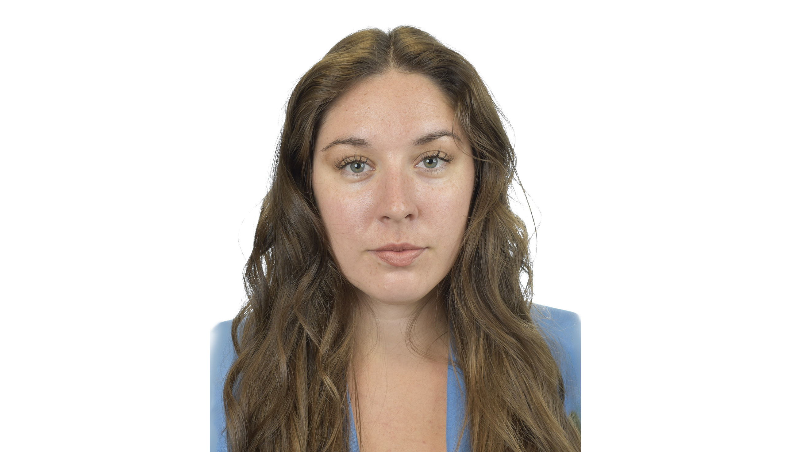 Mörkblond kvinna med långt, lockigt hår och ljusblå kavaj står mot vit bakgrund. Foto