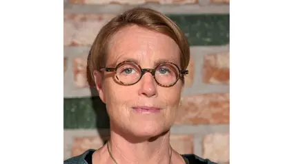 Malin Hultberg, senior lecturer in horticultural science with a focus on food production collaboration, in a portrait photo with a neutral expression. She is wearing round glasses and has short, light hair. The background is a warm-toned brick wall.
